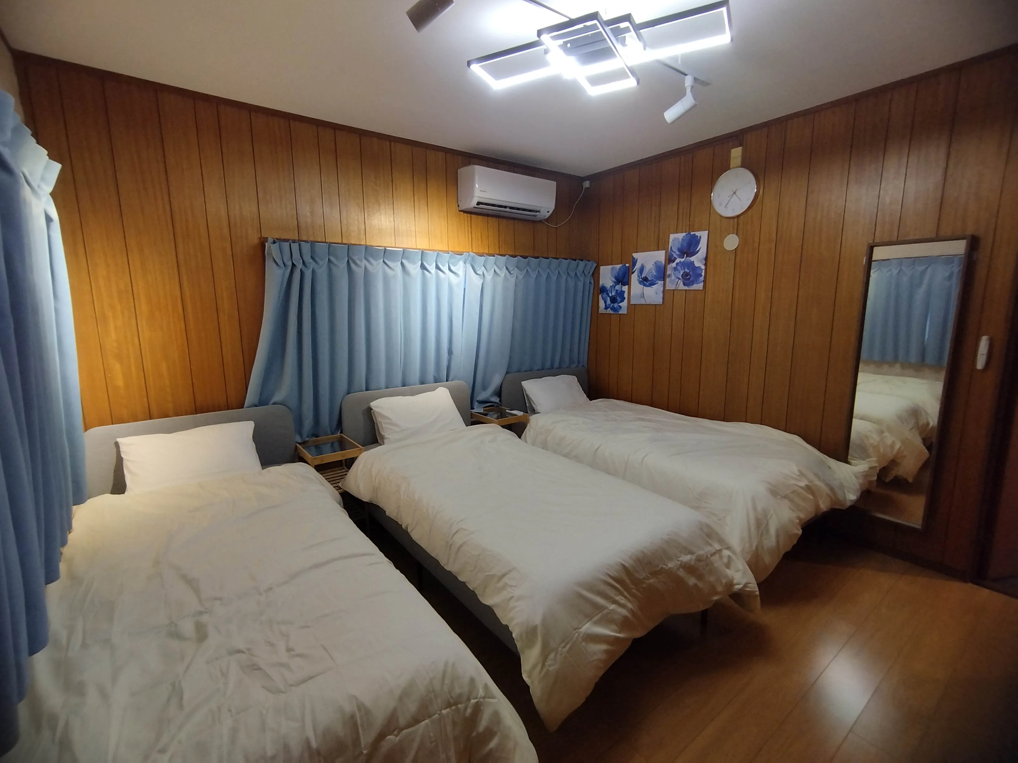 A bedroom with three beds and white bedding