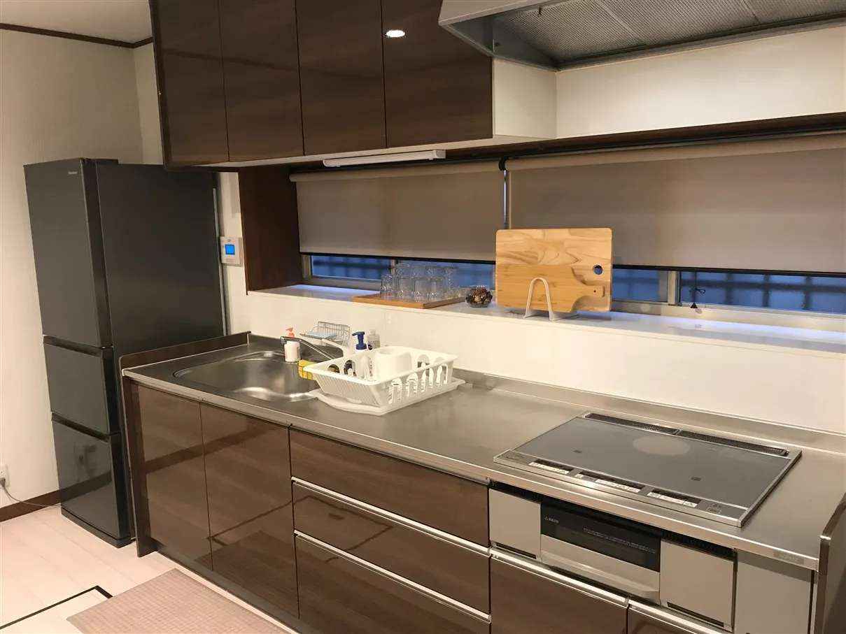 A kitchen with a refrigerator, sink, and cooking counter.
